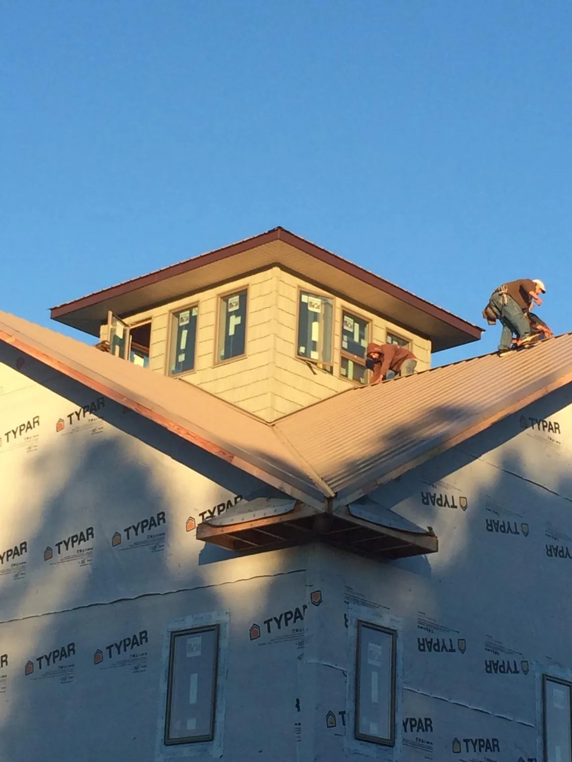 Roofers working around a rooftop cupola on a new metal roof at sunset — Roof Waterproofing in Windsor by Roofing Brothers